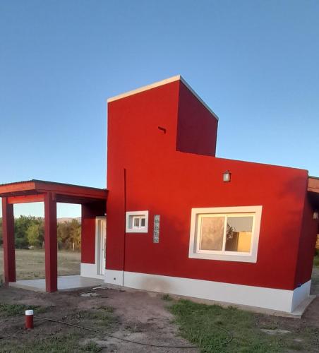 een rood huis met een groot raam aan de zijkant bij Cabañas Tinkuy I in Cortaderas