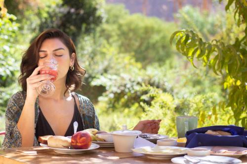 a woman sitting at a table drinking from a glass at Hotel Casona Distante in Alcoguaz