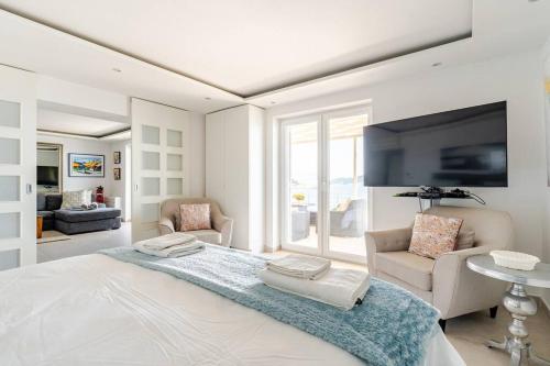 a white bedroom with a large bed and a living room at Blue Views Villa with Heated Pool & Jacuzzi in Dubrovnik