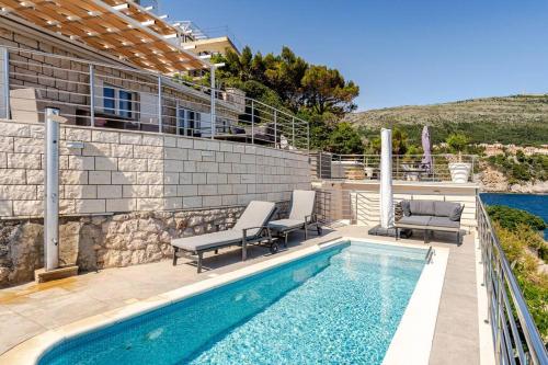 a swimming pool with two chairs and a house at Blue Views Villa with Heated Pool & Jacuzzi in Dubrovnik