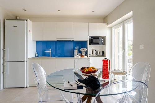 a kitchen with a glass table with chairs and blue cabinets at Blue Views Villa with Heated Pool & Jacuzzi in Dubrovnik