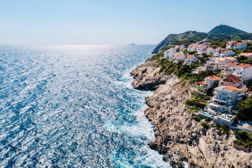 a group of houses on a cliff next to the ocean at Blue Views Villa with Heated Pool & Jacuzzi in Dubrovnik