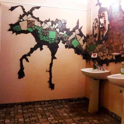 a bathroom with a mosaic dinosaur on the wall at La Revuelta in Amaicha del Valle