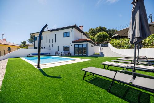 a house with a swimming pool and an umbrella at Paiva River Suítes in Alvarenga