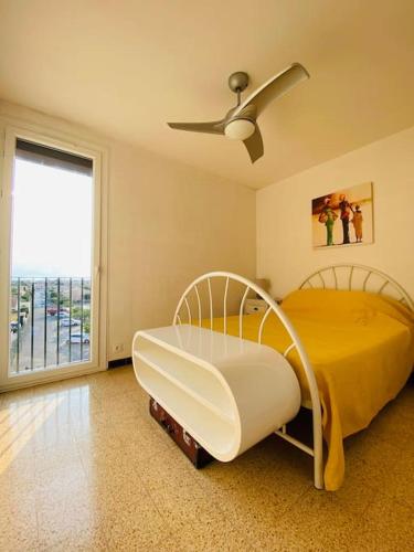 - une chambre avec un lit, un ventilateur et une fenêtre dans l'établissement Grand appartement proche du Port, à Saint-Cyprien