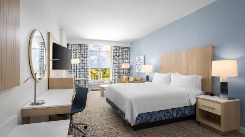 a hotel room with a bed and a desk and a mirror at Holiday Inn Resort Fort Walton Beach by IHG in Fort Walton Beach