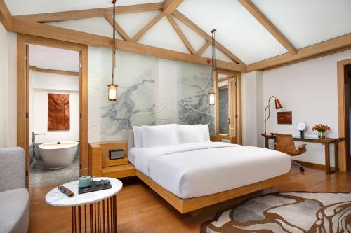 a bedroom with a large white bed and a bathroom at Hotel Indigo Lijiang Ancient Town by IHG in Lijiang
