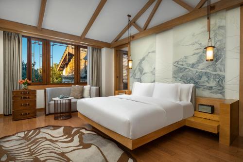 a bedroom with a large bed and a living room at Hotel Indigo Lijiang Ancient Town by IHG in Lijiang
