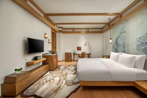 a hotel room with a bed and a tv at Hotel Indigo Lijiang Ancient Town by IHG in Lijiang