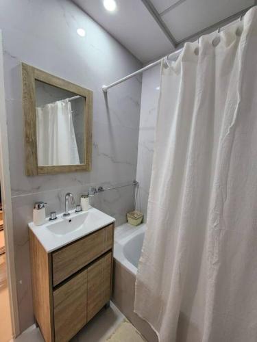 a bathroom with a white shower curtain and a sink at Ohiggins Bahía Premium in Bahía Blanca