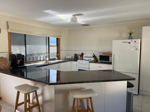 a kitchen with a white refrigerator and two bar stools at Shore Beats Work in Robe