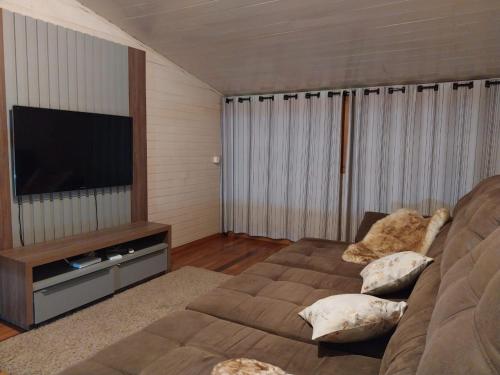 a living room with a couch and a flat screen tv at Super Casa de 3 Quartos ao Lado da Igreja Matriz in Urubici