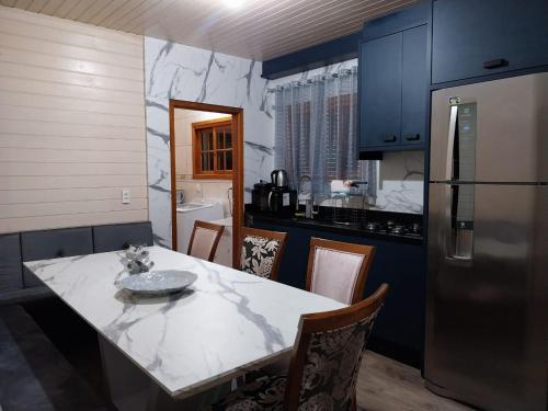 a kitchen with a white table and a refrigerator at Super Casa de 3 Quartos ao Lado da Igreja Matriz in Urubici