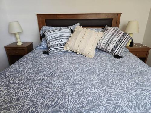 a bed with a blue and white blanket and pillows at Departamento equipado Parque Oriente in Temuco