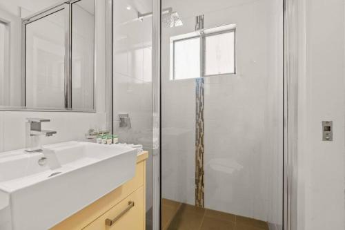 a bathroom with a sink and a glass shower at Yanti at Nightcliff - Foreshore - Pool - Shops & Cafe in Nightcliff