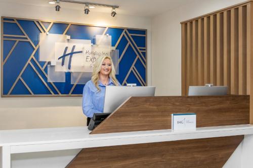 a woman sitting at a desk with a laptop at Holiday Inn Express & Suites - Tuscaloosa-University by IHG in Tuscaloosa