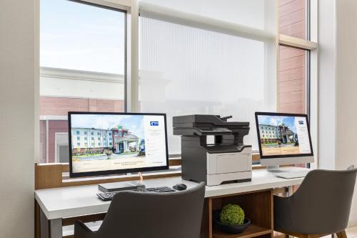 an office with two monitors and a printer on a desk at Holiday Inn Express & Suites - Tuscaloosa-University by IHG in Tuscaloosa