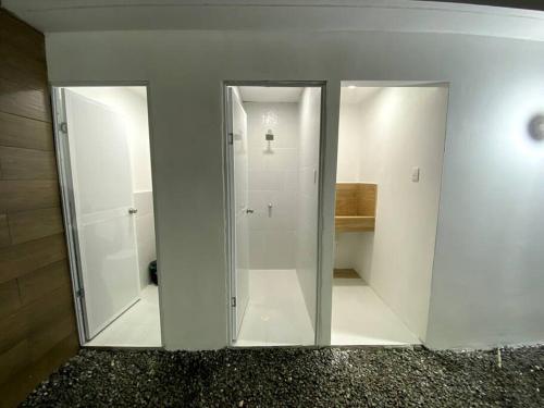 a bathroom with white walls and glass doors at Casa de Playa Nueva, Confortable y Económica in Crucita