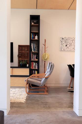 a chair in a living room with a book shelf at Tuis Nest Auckland NZ in Auckland
