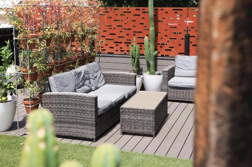 a patio with a couch and chairs and plants at Tuis Nest Auckland NZ in Auckland