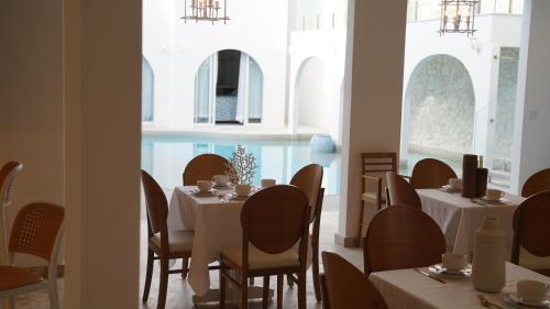 a restaurant with white tables and chairs and windows at D'Blue Búzios Hotel Boutique in Búzios