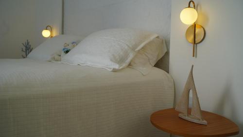 a bed with white sheets and a table with a lamp at D'Blue Búzios Hotel Boutique in Búzios