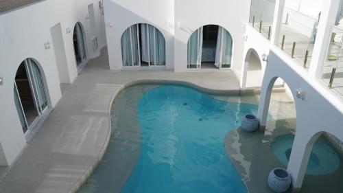 an indoor swimming pool with blue water in a building at D'Blue Búzios Hotel Boutique in Búzios