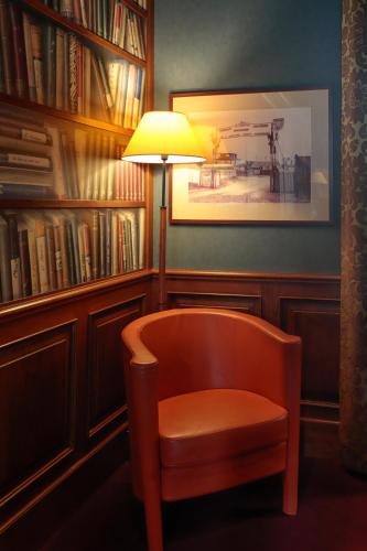 a chair sitting next to a lamp in a library at Hotel Le Paddock in Magny-Cours