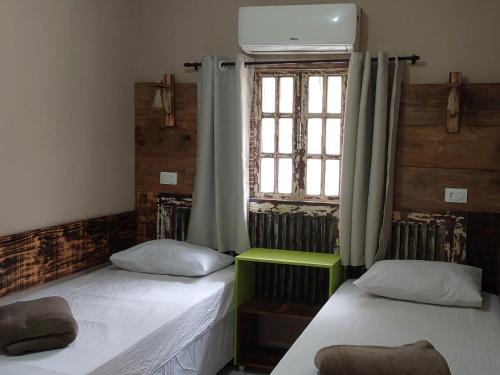 two beds in a room with a window at Casa temporada Araçoiaba in Araçoiaba