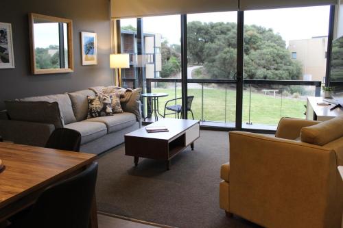 a living room with a couch and a table at Coastal Cove Retreat - with heated pool near Hot Springs & Golf in Fingal