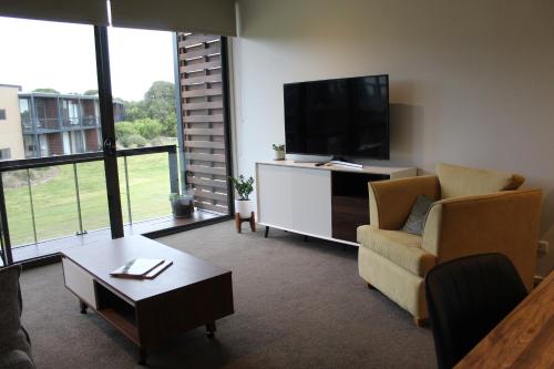 a living room with a television and a couch and a table at Coastal Cove Retreat - with heated pool near Hot Springs & Golf in Fingal