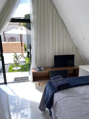 a bedroom with a bed and a desk with a television at Villa Suíça Ibiapaba in Tianguá