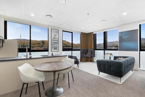 a living room with a table and chairs and windows at 12th Avenue Suites in Queenstown
