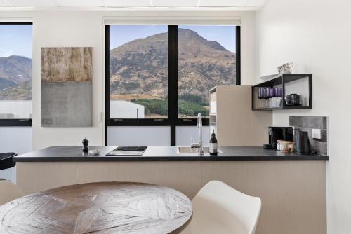 a kitchen with a counter with a table and some windows at 12th Avenue Suites in Queenstown