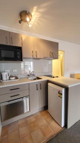 a kitchen with white cabinets and a counter top at Manukau Motor Lodge in Auckland