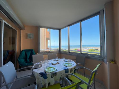 une salle à manger avec une table, des chaises et des fenêtres dans l'établissement T3 à Sète: Face Mer, WIFI, Parking - FR-1-338-424, à Sète