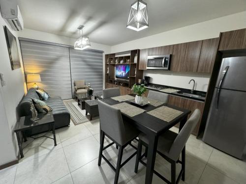 a kitchen and living room with a table and a couch at Departamento Nuevo Frente al TSM in Torreón
