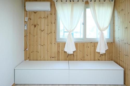 a room with a window and a white mattress at Ronnie Pension in Taean