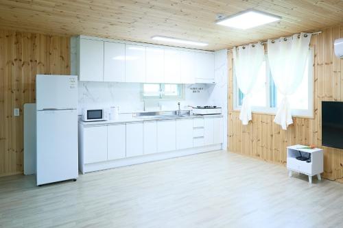 a kitchen with white cabinets and a white refrigerator at Ronnie Pension in Taean