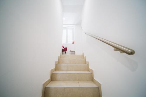 a staircase in a white room with a red chair at Korkyra Harbour Rooms in Korčula