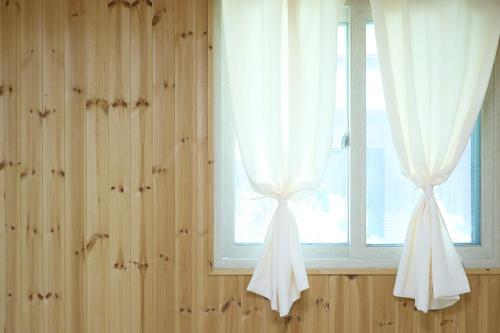a window with white curtains in a room at Ronnie Pension in Taean