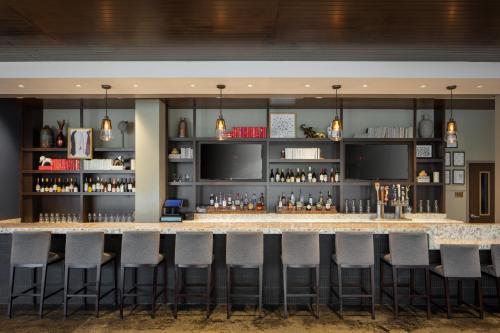 a bar at a hotel with stools at Hotel Indigo Tuscaloosa Downtown by IHG in Tuscaloosa