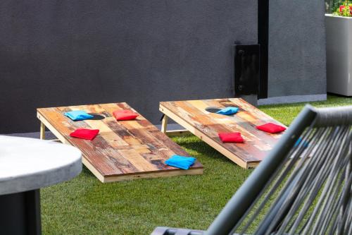 two picnic tables with red and blue cushions on the grass at Hotel Indigo Tuscaloosa Downtown by IHG in Tuscaloosa