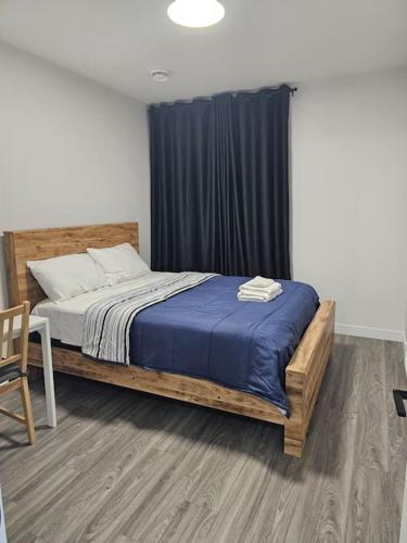 a bedroom with a wooden bed with a blue blanket at Lovely 2 Bedroom Suite in Calgary in Calgary