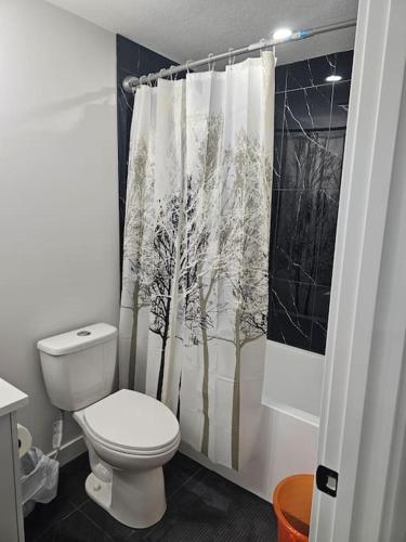 a bathroom with a toilet and a shower curtain at Lovely 2 Bedroom Suite in Calgary in Calgary