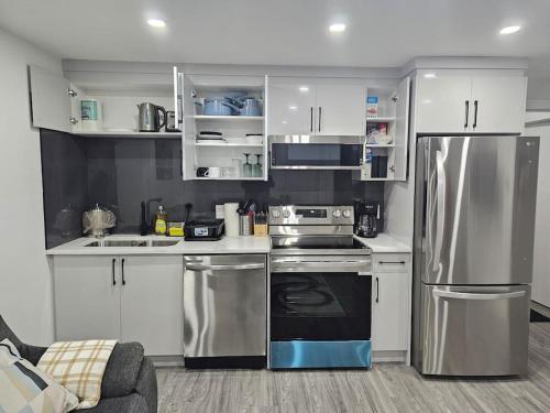 a kitchen with stainless steel appliances and white cabinets at Lovely 2 Bedroom Suite in Calgary in Calgary