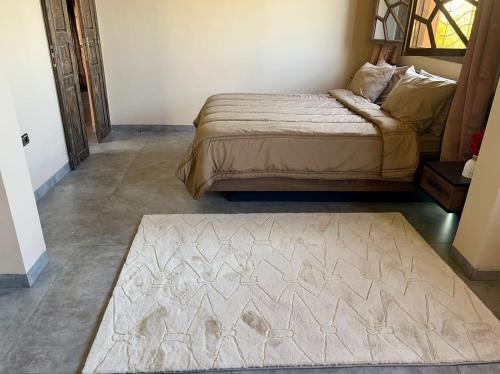 a bedroom with a bed and a rug on the floor at فيلا عبد الله غيات in Had Abdallah Rhiat