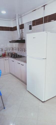 a kitchen with a white refrigerator in a room at Cléopâtre la chrétienne in Tefeschoun