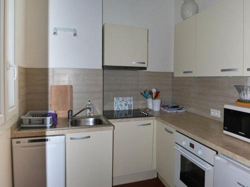 une cuisine avec des armoires blanches et un évier dans l'établissement Le Lavandou: T2 4 couchages proche plage avec WIFI - FR-1-803-39, au Lavandou