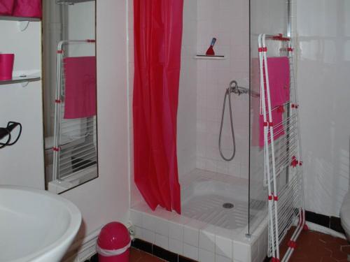 La salle de bains est pourvue d'une douche avec rideau de douche rouge. dans l'établissement Le Lavandou: T2 4 couchages proche plage avec WIFI - FR-1-803-39, au Lavandou